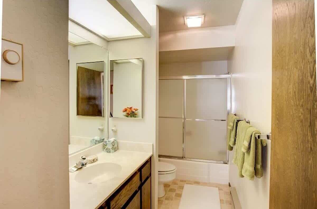 A bathroom with a sink, mirror, and shower.