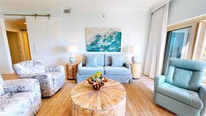 A living room with a sofa, two armchairs, a coffee table, and a painting on the wall.