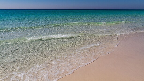 A beach with clear water and a sandy shore.