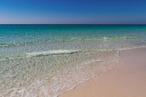 A beach with clear water and a sandy shore.