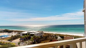 A coastal view from a balcony overlooking a beach with clear skies.