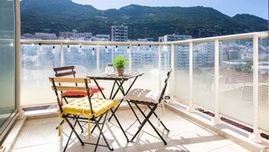 A balcony with a table and chairs, a potted plant, and a view of a cityscape and mountains. - Luxury modern apartment with exceptional views! (Gibraltar)