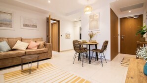 A living room with a sofa, coffee table, and a dining area with chairs and a table. - Luxury modern apartment with exceptional views! (Gibraltar)