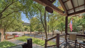A covered outdoor area with a wooden deck, a bench, and an American flag. - Lil Kahuna Rr 7465 1 Bedroom Home by RedAwning (New Braunfels)