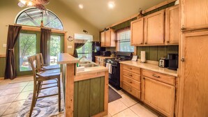 Une cuisine avec des armoires en bois, une cuisinière, un évier et un ventilateur de plafond.