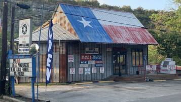 A rustic building with a Texas flag motif, featuring signs for a restaurant, ice cream, and rental services.