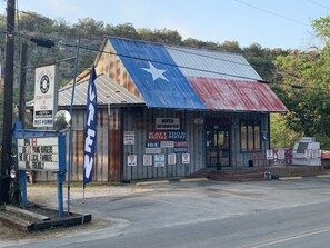 Ein rustikales Gebäude mit Texas-Flagge, mit Schildern für ein Restaurant, Eis und Vermietungsservice.