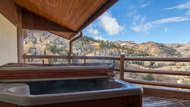 A hot tub on a wooden deck with a view of a mountainous landscape. - Flagstaff Two Bedroom 2 Apartment Hotel by RedAwning (Park City)