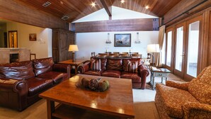 A spacious living room with a wooden ceiling, leather sofas, a wooden coffee table, and a dining area with a chandelier. - Flagstaff Two Bedroom 2 Apartment Hotel by RedAwning (Park City)