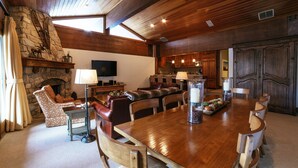 A spacious living room with a stone fireplace, wooden ceiling, and a large dining table with chairs. - Flagstaff Two Bedroom 2 Apartment Hotel by RedAwning (Park City)