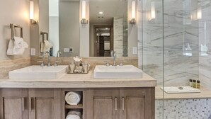 A modern bathroom with two sinks, a large mirror, and a glass shower enclosure.