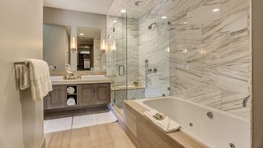 A modern bathroom with a large bathtub, a glass-enclosed shower, and a vanity with a mirror.
