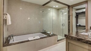 A modern bathroom with a glass-enclosed shower, a freestanding bathtub, and a vanity with a marble countertop.