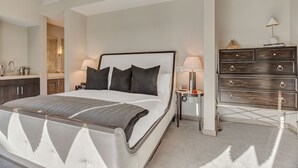 A modern bedroom with a large bed, bedside tables, a dresser, and a mirror.