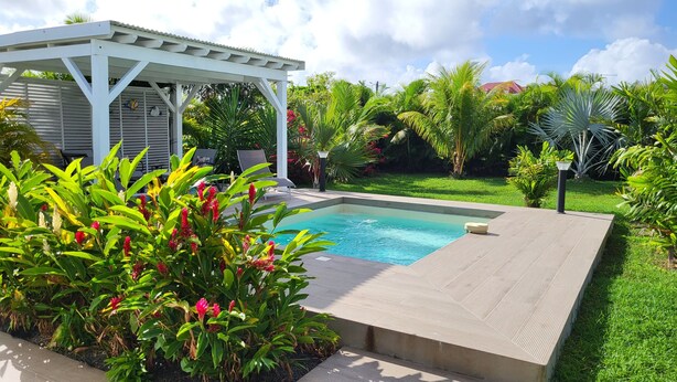 A swimming pool with a wooden deck, surrounded by lush greenery and a white gazebo. - La Kaz a Kikite - Magnificent luxury villa with swimming pool (Saint François)