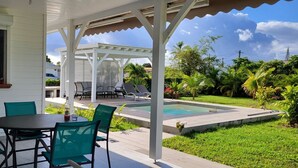 A covered patio with a pool, outdoor seating, and lush greenery. - La Kaz a Kikite - Magnificent luxury villa with swimming pool (Saint François)