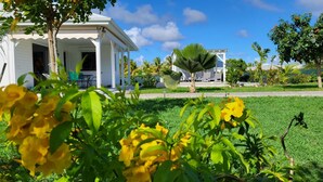 A white building with a covered porch, surrounded by lush greenery and palm trees. - La Kaz a Kikite - Magnificent luxury villa with swimming pool (Saint François)