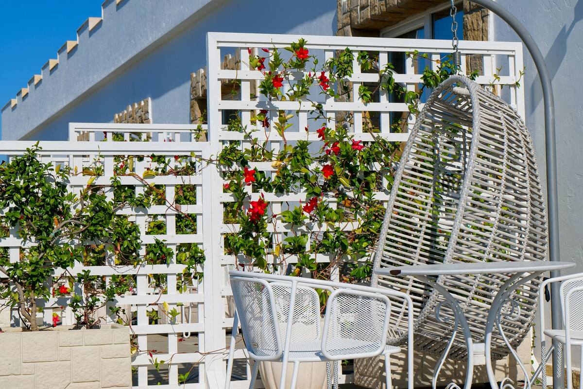 Un set tavolo e sedia in metallo bianco davanti a un recinto bianco con fiori rossi.