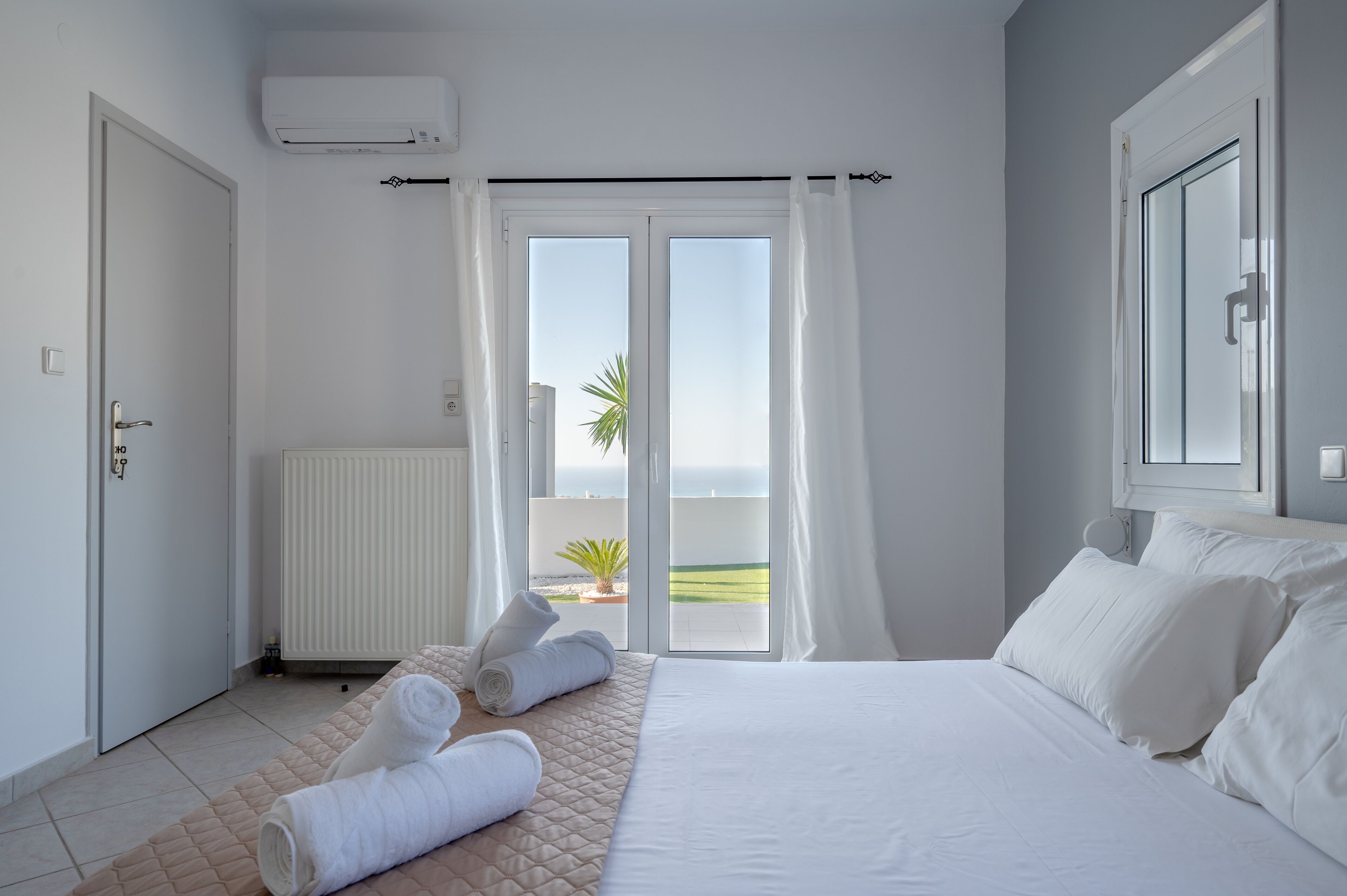 Une chambre d’hôtel avec un lit, une fenêtre avec des rideaux, un radiateur et une vue sur l’extérieur.