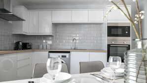 A modern kitchen with grey cabinetry, a dishwasher, a coffee maker, and a microwave. - A spacious and stylish 2 bedroom, 2 bathroom duplex apartment (Grassington)