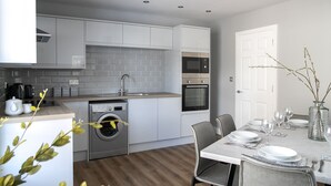 A modern kitchen with grey cabinets, a built-in oven, and a washing machine. - A spacious and stylish 2 bedroom, 2 bathroom duplex apartment (Grassington)