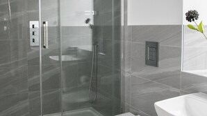 A modern bathroom with a glass-enclosed shower, a white toilet, and a sink. - A spacious and stylish 2 bedroom, 2 bathroom duplex apartment (Grassington)
