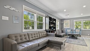 A modern living room with a sectional sofa, a coffee table, and a bookshelf. - ❤️ Spacious Island Cottage at Indian Lake ❤️ (Huntsville)