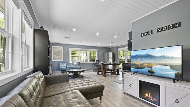 A modern living room with a large flat-screen TV, a fireplace, and a comfortable seating area. - ❤️ Spacious Island Cottage at Indian Lake ❤️ (Huntsville)