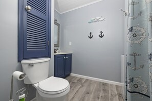 Ein Badezimmer mit Toilette, einem Schrank und einer Duschkabine mit Meeresmotiven.