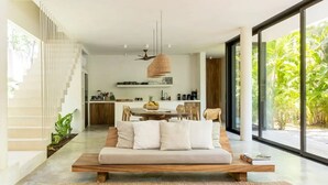 A modern living room with a sofa, coffee table, and a dining area in the background. - Casa Areca, 4 bed/4.5 bath World Renowned Design Villa, Pool, Rooftop, 24/7Guard (Tulum)