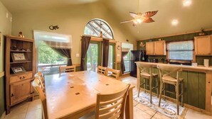A kitchen with a dining table, chairs, a refrigerator, and a window with curtains. - RR 7465 Lil Kahuna (New Braunfels)