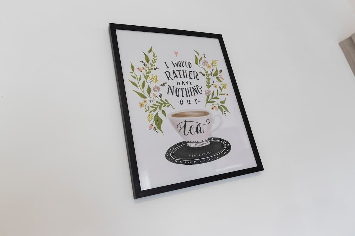A framed quote with a cup of tea and floral decorations.