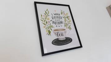 A framed quote with a cup of tea and floral decorations.