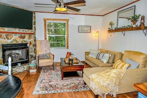 A cozy living room with a stone fireplace, a sofa, a coffee table, and a patterned rug. - Awesome Views • HOT TUB • Outdoor Shower • Fast Wifi (Murphy)