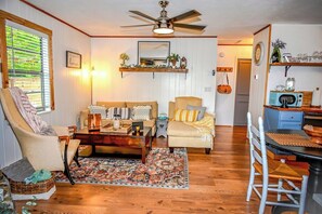 A living room with a sofa, armchair, coffee table, and a dining area with a table and chairs. - Awesome Views • HOT TUB • Outdoor Shower • Fast Wifi (Murphy)