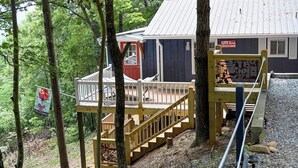 Une cabane dotée d’une terrasse en bois et d’un escalier menant à un porche.