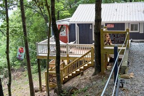 Une cabane dotée d’une terrasse en bois et d’un escalier menant à un porche.