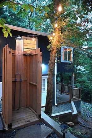 A wooden outdoor shower with a waterfall feature, a wooden deck, and a tree with hanging lights. - Awesome Views • HOT TUB • Outdoor Shower • Fast Wifi (Murphy)