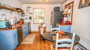 Une cuisine compacte avec un coin repas, un plancher en bois et une fenêtre qui laisse entrer la lumière naturelle.