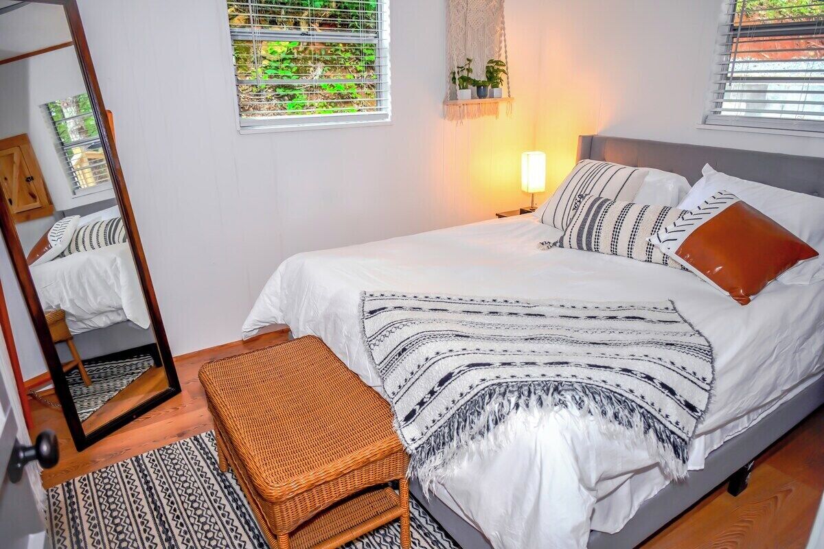 A neatly arranged bedroom with a bed, bedside table, and a mirror.
