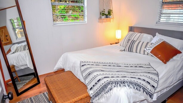 Une chambre bien rangée, avec un lit, une table de chevet et un miroir.