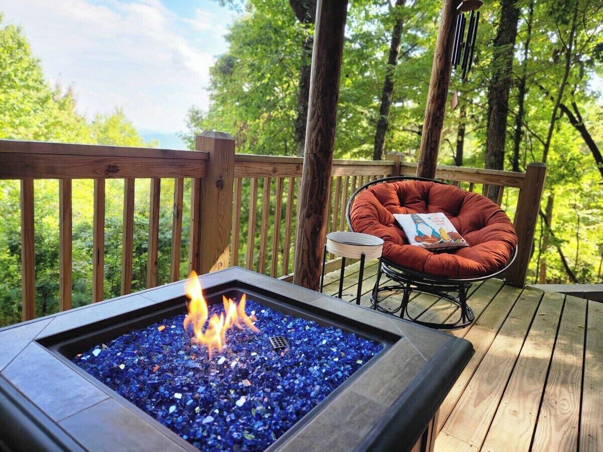 A deck with a fire feature, a cushioned chair, and a small table.