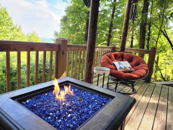 A deck with a fire feature, a cushioned chair, and a small table. - Awesome Views • HOT TUB • Outdoor Shower • Fast Wifi (Murphy)