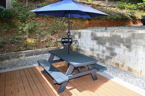 A picnic table with a grill and umbrella on a wooden deck. - Awesome Views • HOT TUB • Outdoor Shower • Fast Wifi (Murphy)