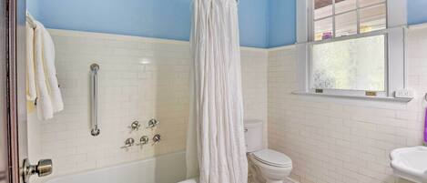 A bathroom with a bathtub, shower, and toilet.