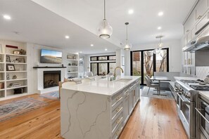 A modern kitchen with a large island, built-in appliances, and a fireplace. - Upmarket Large Modern Home with a Spacious Office & Garden (Philadelphia)