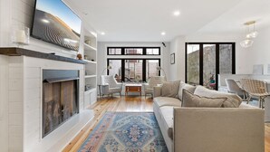 Ein modernes Wohnzimmer mit Kamin, großem Fernseher und gemütlichem Sitzbereich.