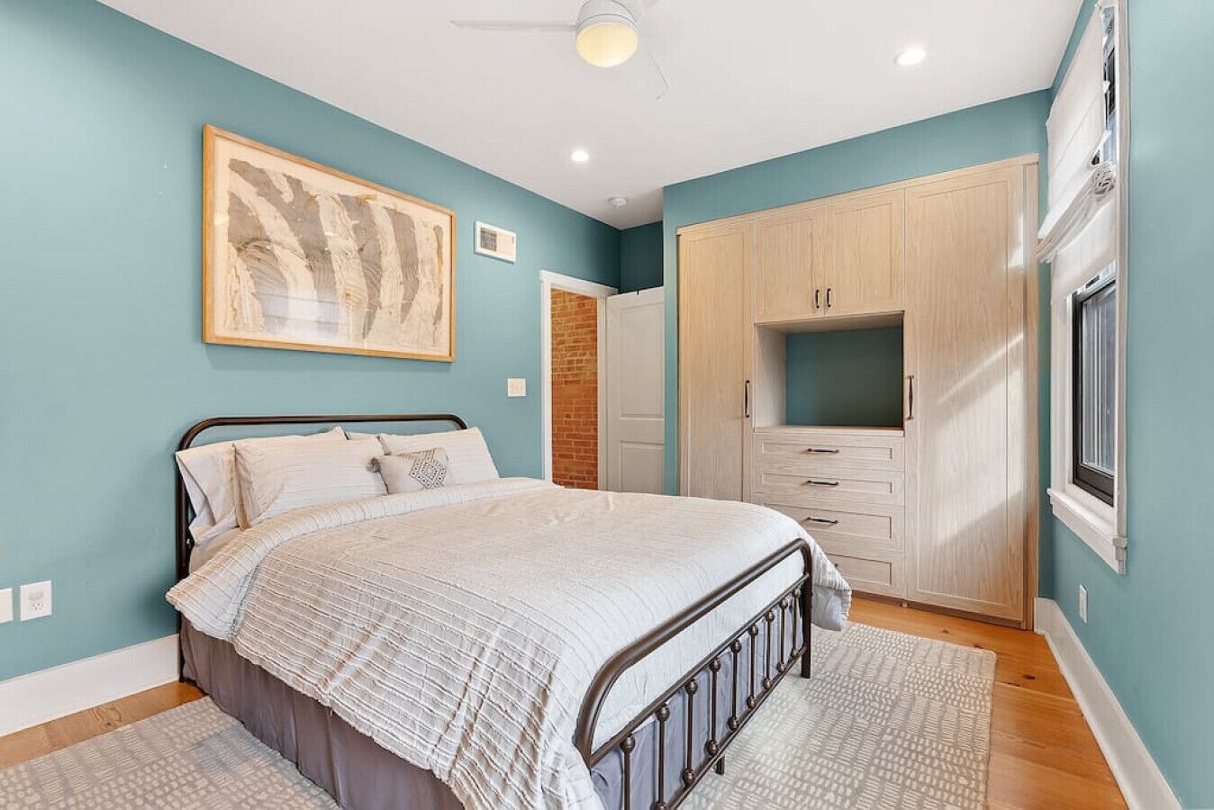 Ein Schlafzimmer mit Bett, Kleiderschrank und einem großen Fenster.