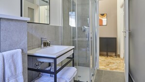 Un baño moderno con cabina de ducha de vidrio, un lavabo blanco y un espejo encima.
