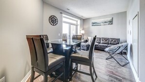 A modern dining area with a glass table and leather chairs, a leather sofa, and a large window with a view.